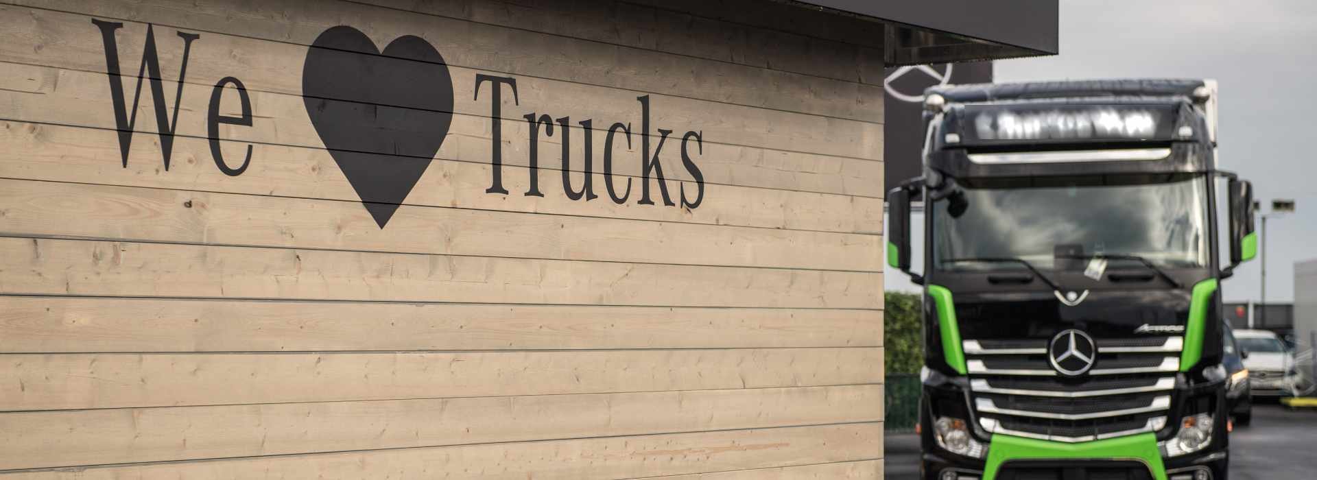 We love Trucks Bild an Holzwand Mercedes-Benz Actross im Hintergrund